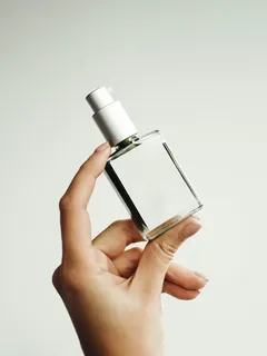Mano femminile che tiene una bottiglia di profumo elegante