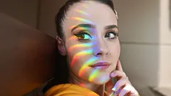 Donna con top giallo guarda arcobaleno nel cielo limpido