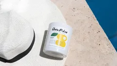 Integratore vitamina B sul bordo piscina accanto a cappello bianco