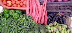 Verdure fresche tra cui pomodori, carote, peperoni e melanzane in un mercato