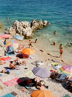 Spiaggia affollata con molte persone e ombrelloni colorati