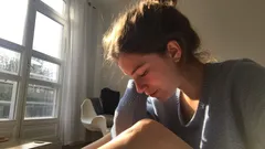 Ragazza concentrata che studia vicino a finestra luminosa in casa