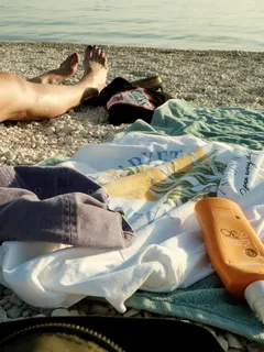 Uomo sdraiato sulla spiaggia accanto a un corso d'acqua