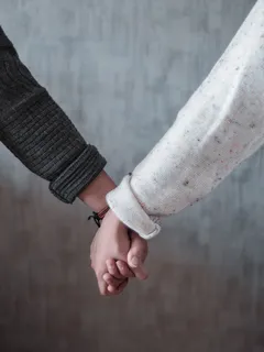 due persone che si tengono per mano, uomo con maglia nera e donna con maglia bianca