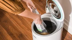 Persona che getta sacchetto nei rifiuti in contenitore domestico