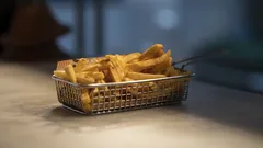 Patatine fritte croccanti in cestino metallico su tavolo